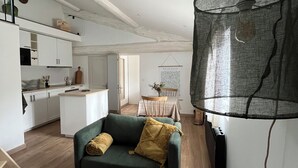 Un salon moderne avec un canapé vert, une table basse et un coin repas comprenant une table et des chaises.