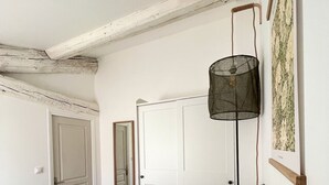Une chambre à coucher avec un lit, une lampe suspendue, une porte et un tableau encadré au mur.