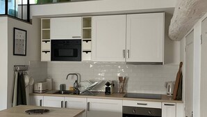 Une cuisine moderne avec des meubles blancs, un four noir et un plan de travail en bois.