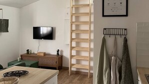 Une cuisine moderne avec un plan de travail en bois, une cuisinière encastrée et un téléviseur fixé au mur.