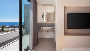 Un baño moderno con un espejo grande, un lavamanos y una ducha. Tiene un balcón con vista al mar.