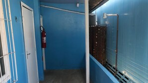 A narrow hallway with blue walls, a white door, and a red fire extinguisher. - Suíte Barros (Navegantes)