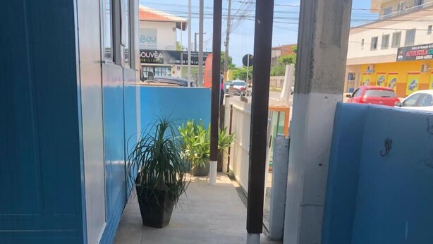 A covered outdoor area with a concrete floor, blue walls, and a potted plant. - Suíte Barros (Navegantes)
