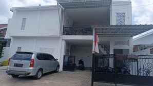 A two-story building with a car parked in front and a motorcycle inside.