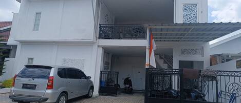 A two-story building with a car parked in front and a motorcycle inside.