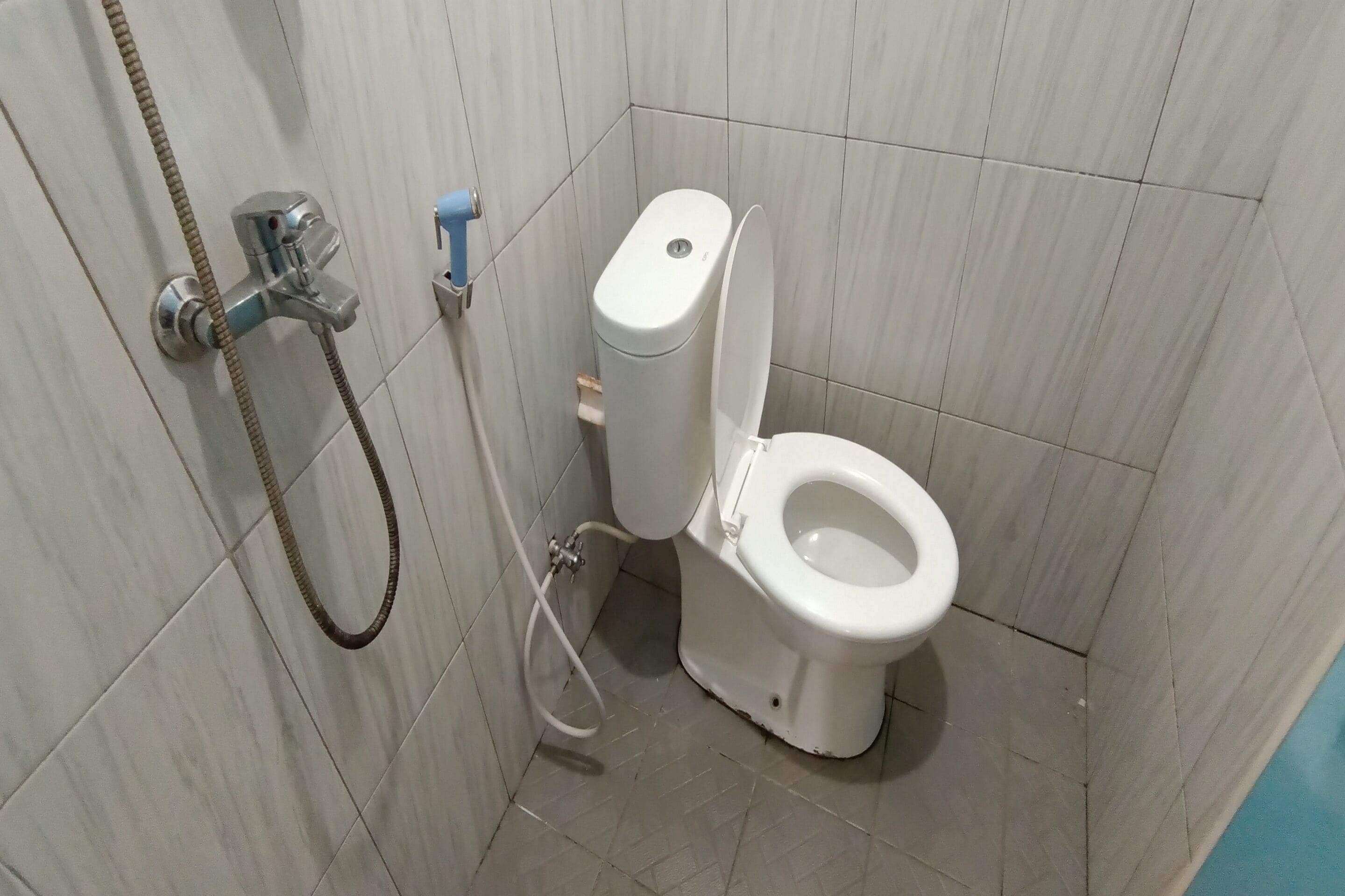 Une petite salle de bain équipée de toilettes, d’une douche et d’un sèche-mains.