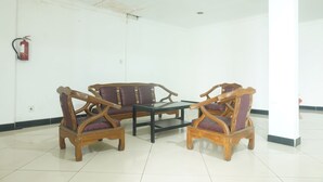 A room with two wooden chairs and a table, white walls, and a fire extinguisher mounted on the wall.