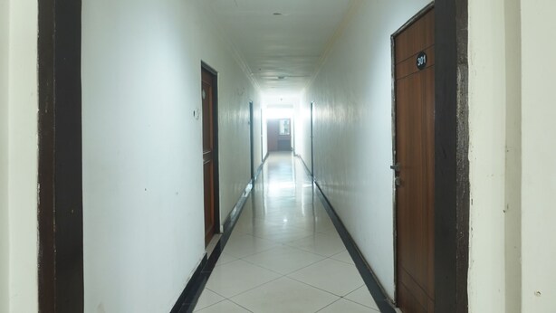 A long, narrow hallway with white walls and a tiled floor. There are two wooden doors on either side, one marked with the number 301.
