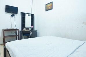 A bedroom with a bed, a TV mounted on the wall, a desk with a chair, and a shelf. - Hotel O Gr Kost Kaladan (Marabahan)
