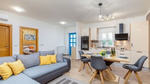 Ein modernes Wohnzimmer mit einer Couch, Sesseln und einem Esstisch.