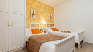 Ein Zimmer mit zwei Betten, Holzboden und einer Wand mit Kunstwerken.