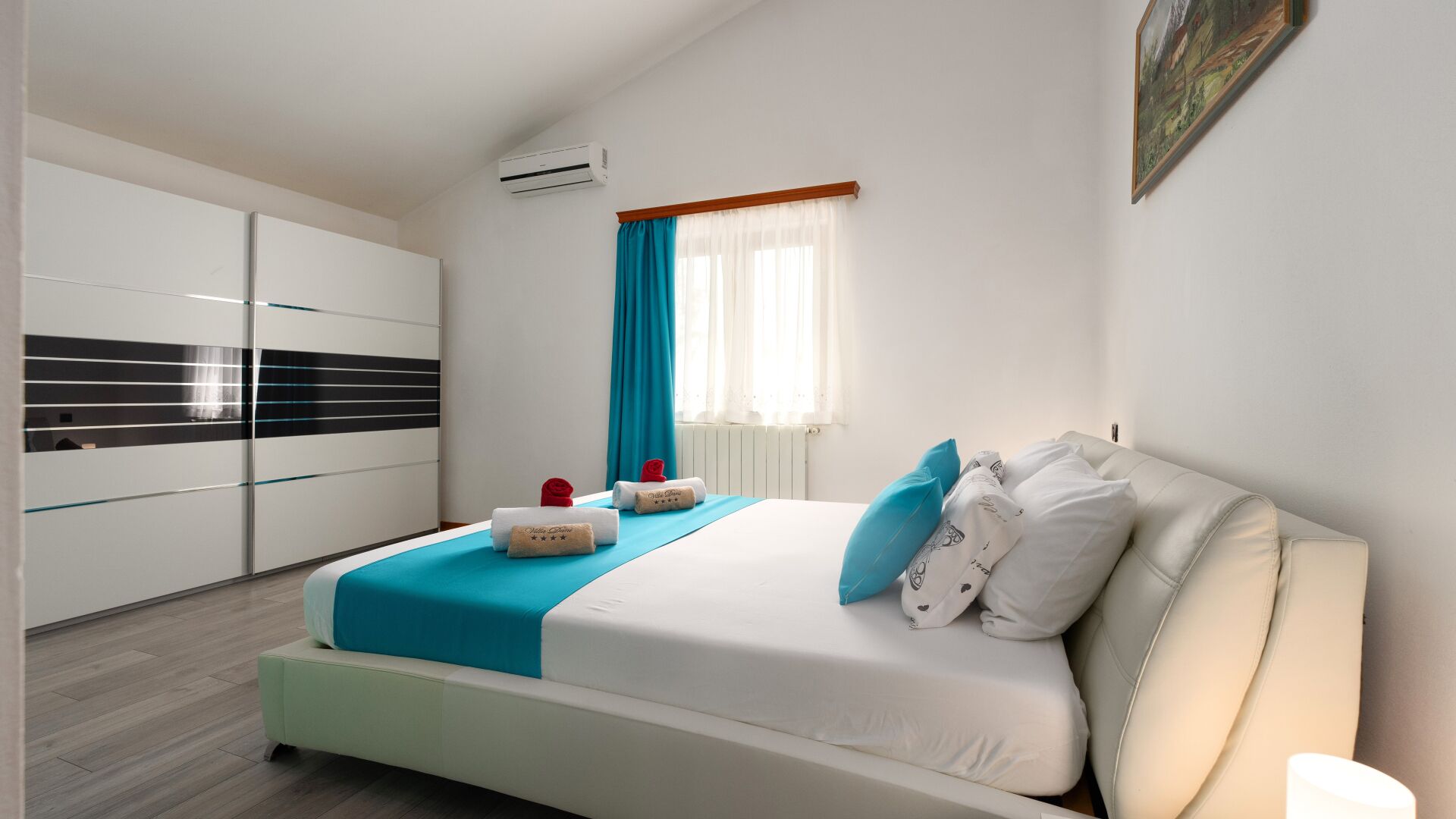Una camera da letto moderna con un letto, un armadio, una finestra con tende e un condizionatore.