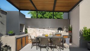 An outdoor patio with a stone wall, a grill, and a dining area with chairs and a table. - Villa Bino&Marija by Villas Guide (Sveti Lovrec)
