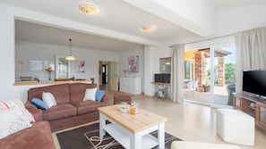 Un salon spacieux avec un canapé marron, une table basse en bois et un téléviseur.