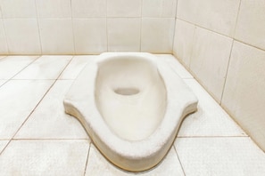 A toilet in a bathroom with white tiles on the floor and walls.