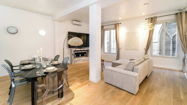 A modern living room with a sofa, a dining table with chairs, and a TV. - A Delightful 2-BR/2BA at Saint Michel - Notre Dame (Paris)