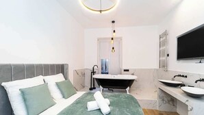 A modern bathroom with a bathtub, a vanity with two sinks, and a large mirror. - A Delightful 2-BR/2BA at Saint Michel - Notre Dame (Paris)