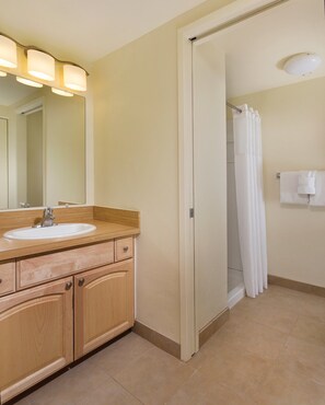 A bathroom with a wooden vanity, a sink, a mirror, and a shower curtain. - Two Bedroom Condo @ Kailua-Kona (Kailua-Kona)
