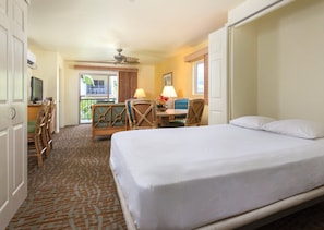 A hotel room with a bed, a desk with a chair, a television, and a balcony with a view. - Two Bedroom Condo @ Kailua-Kona (Kailua-Kona)