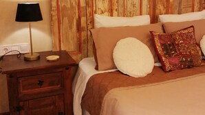 Une chambre à coucher avec une armoire en bois, une table de chevet avec une lampe et un lit avec plusieurs oreillers.