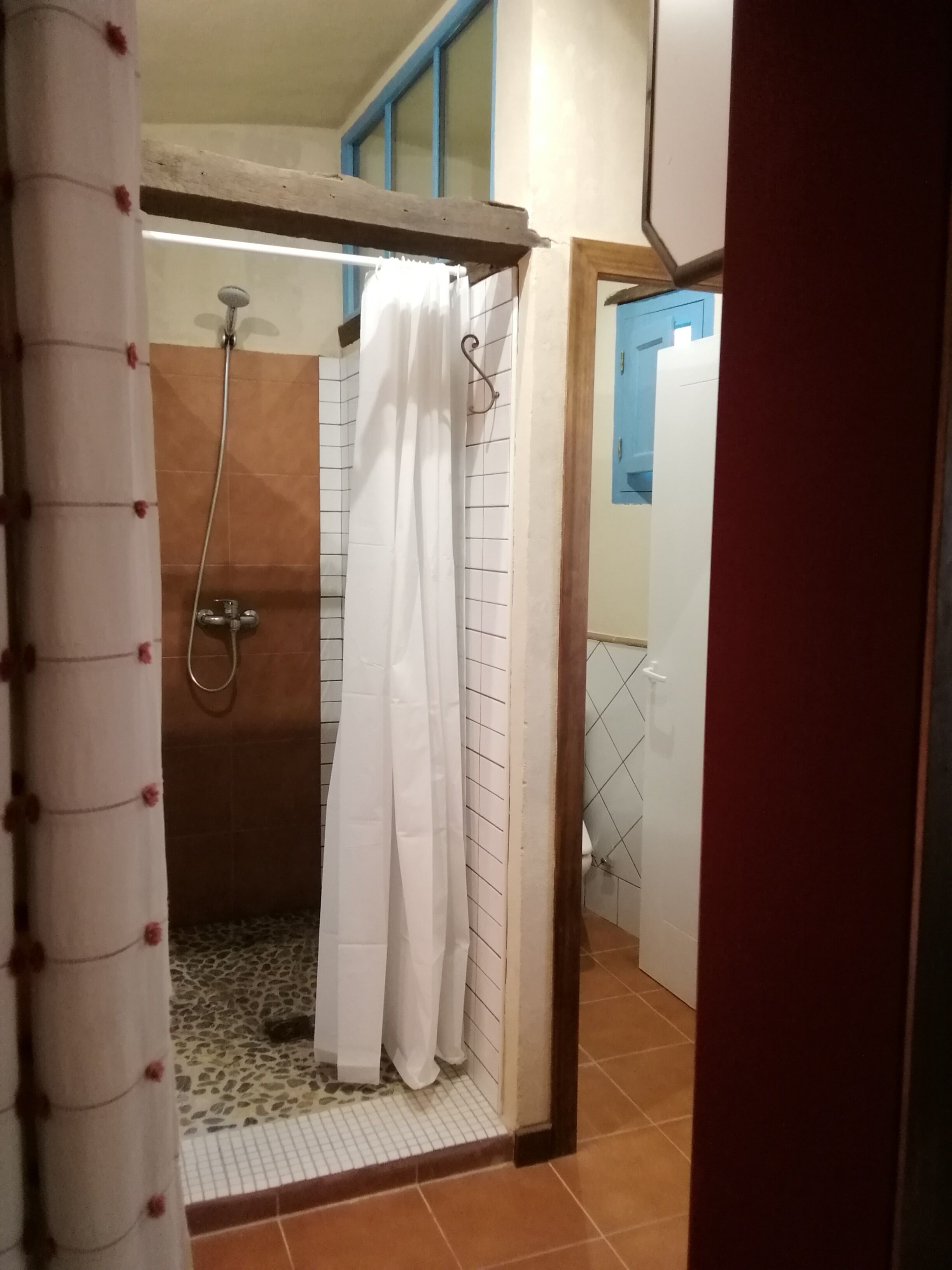 A shower area with a tiled floor, a shower curtain, and a showerhead.