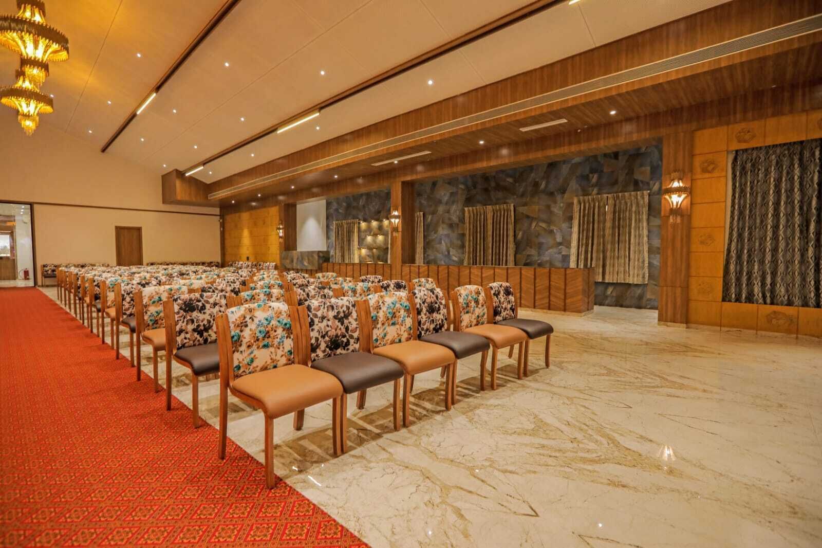 A conference room with rows of chairs, a red carpet, and a stone wall with curtains.