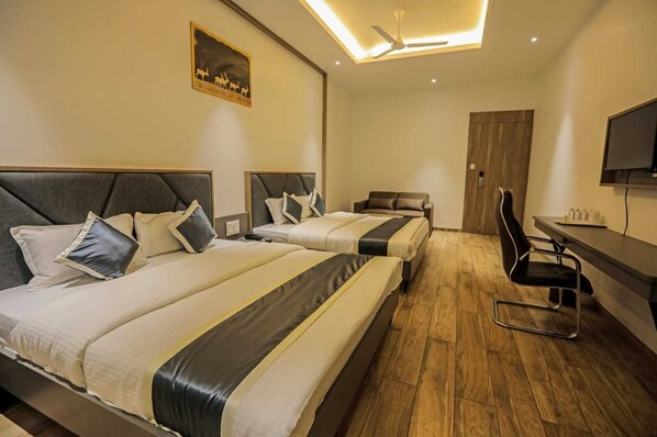 A hotel room with two beds, a desk, a chair, and a television.