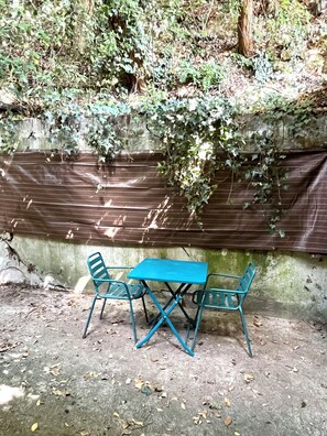 An outdoor seating area with a table and chairs, surrounded by a concrete wall and covered with a brown tarp. - Au Bord de la Rive (Lormont)