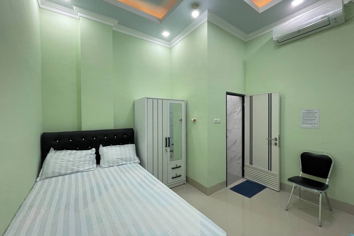 A bedroom with a bed, wardrobe, and a chair.