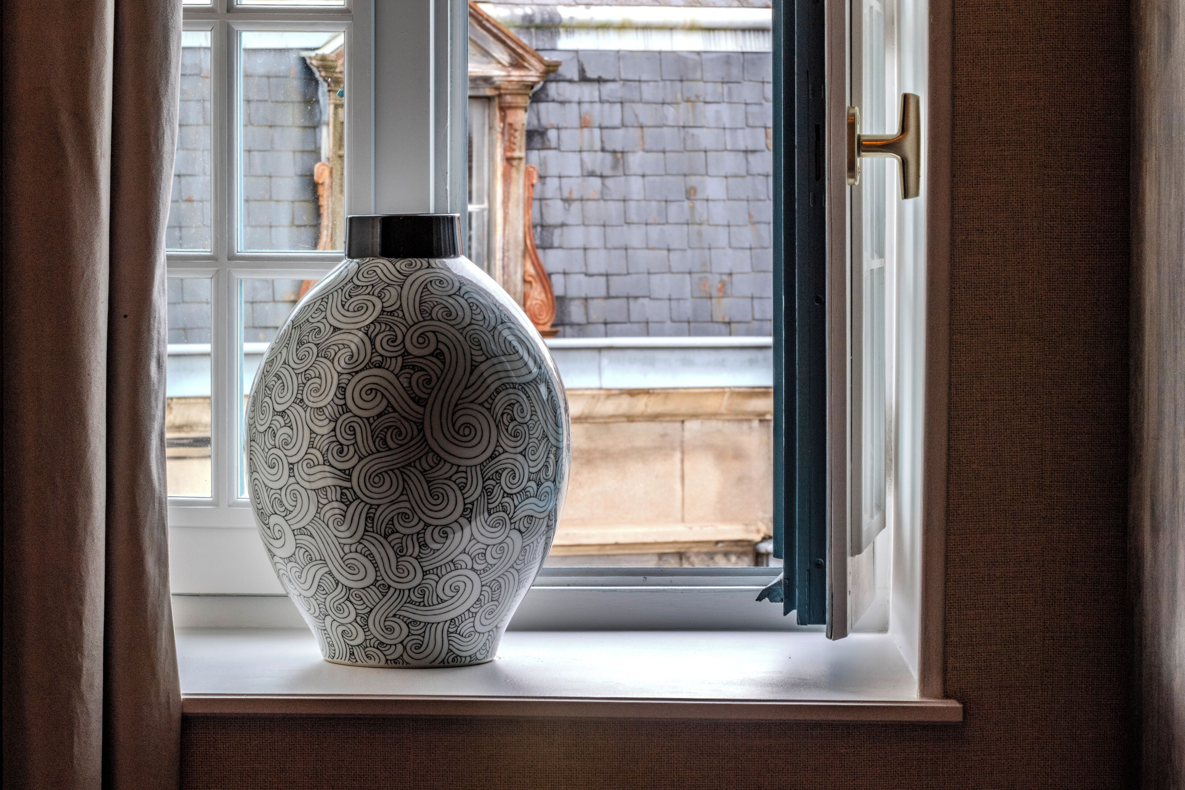 En stor, mønstret vase på et vindueskar.
