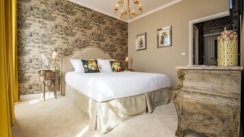 A bedroom with a large bed, a dresser, and a chandelier.