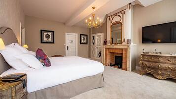 Een hotelkamer met een groot bed, een houten dressoir, een televisie en een open haard.