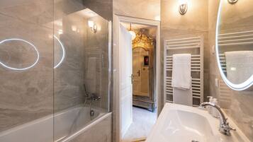 A modern bathroom with a glass-enclosed shower, a white sink with a mirror, and a towel rack.