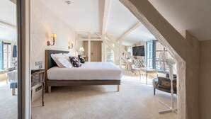 A spacious bedroom with a large bed, a nightstand, a chair, and a desk.
