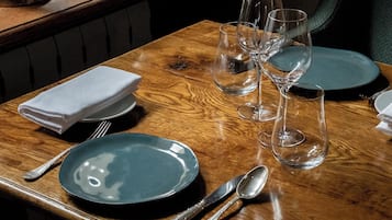 Una tavola da pranzo apparecchiata con cura, con un piatto verde, posate e diversi bicchieri da vino.