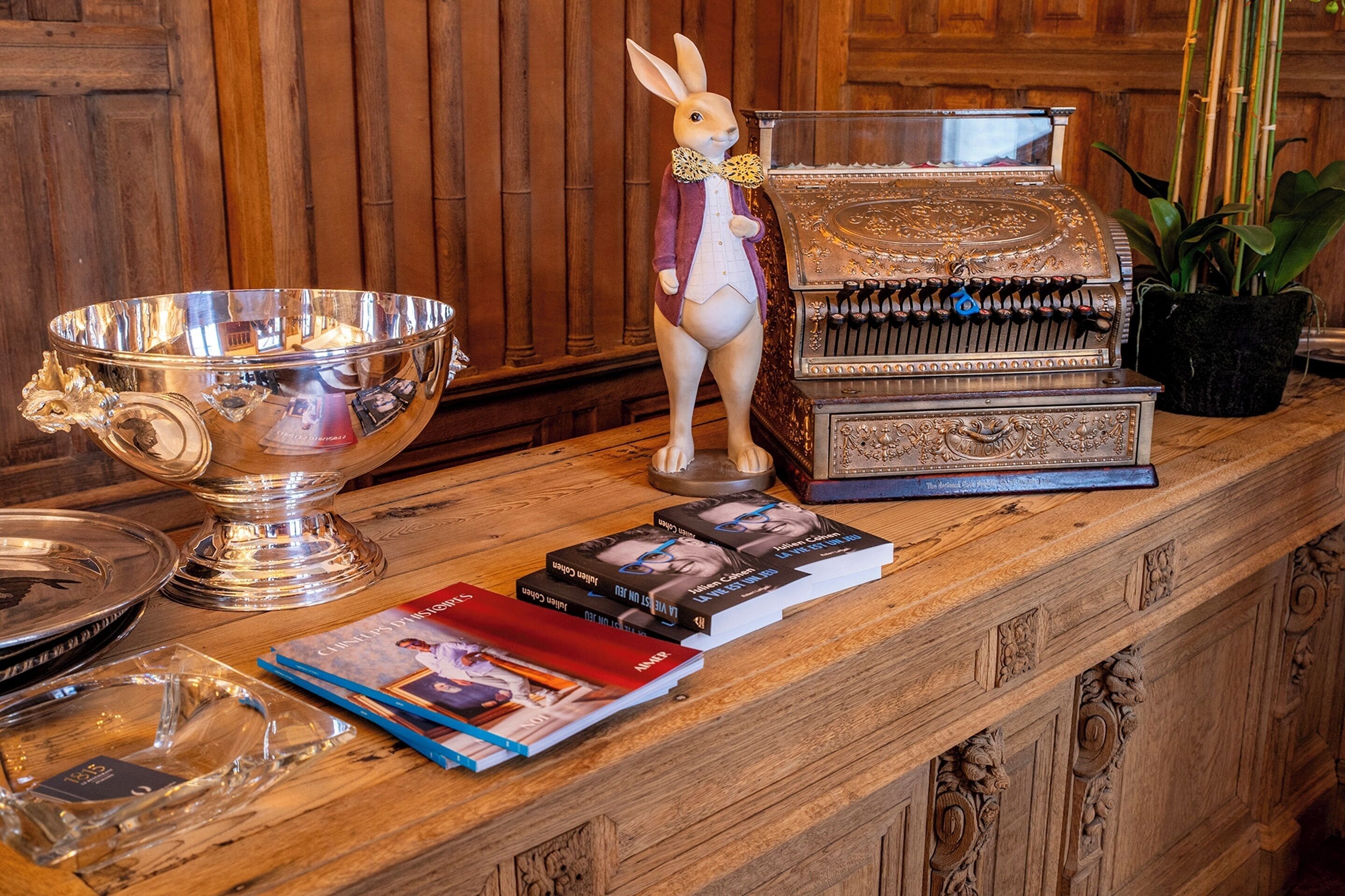 A wooden counter with a silver bowl, a decorative rabbit figurine, a vintage typewriter, and several books.