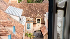 A narrow street with traditional European architecture, including terracotta roofs and stone walls.