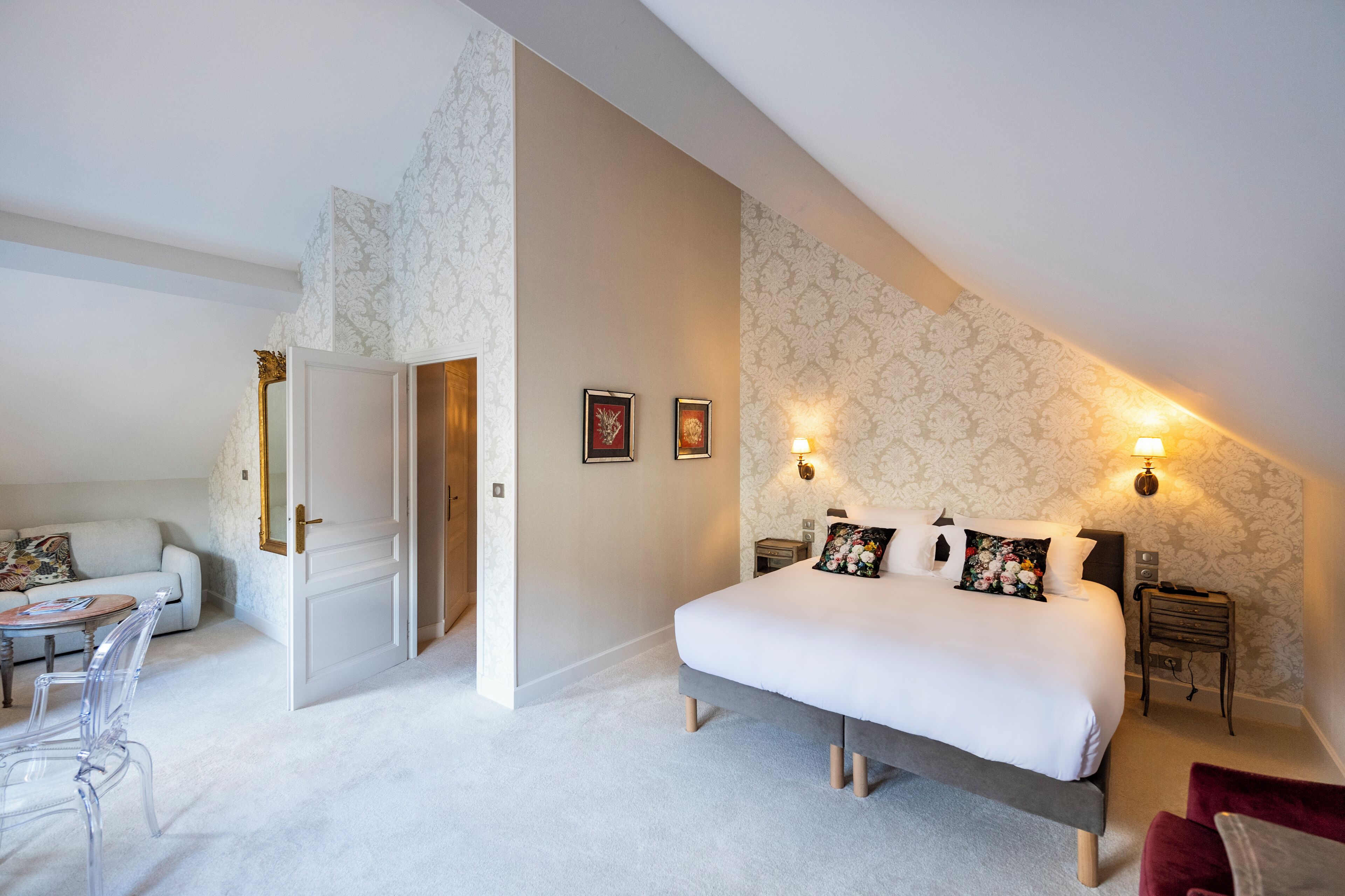 Une chambre à coucher avec un grand lit, des tables de chevet, une commode, une chaise, une petite table et un canapé.