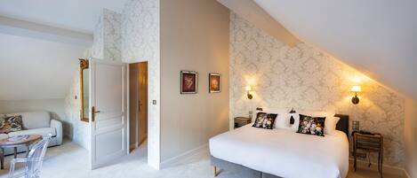 Une chambre à coucher avec un grand lit, des tables de chevet, une commode, une chaise, une petite table et un canapé.