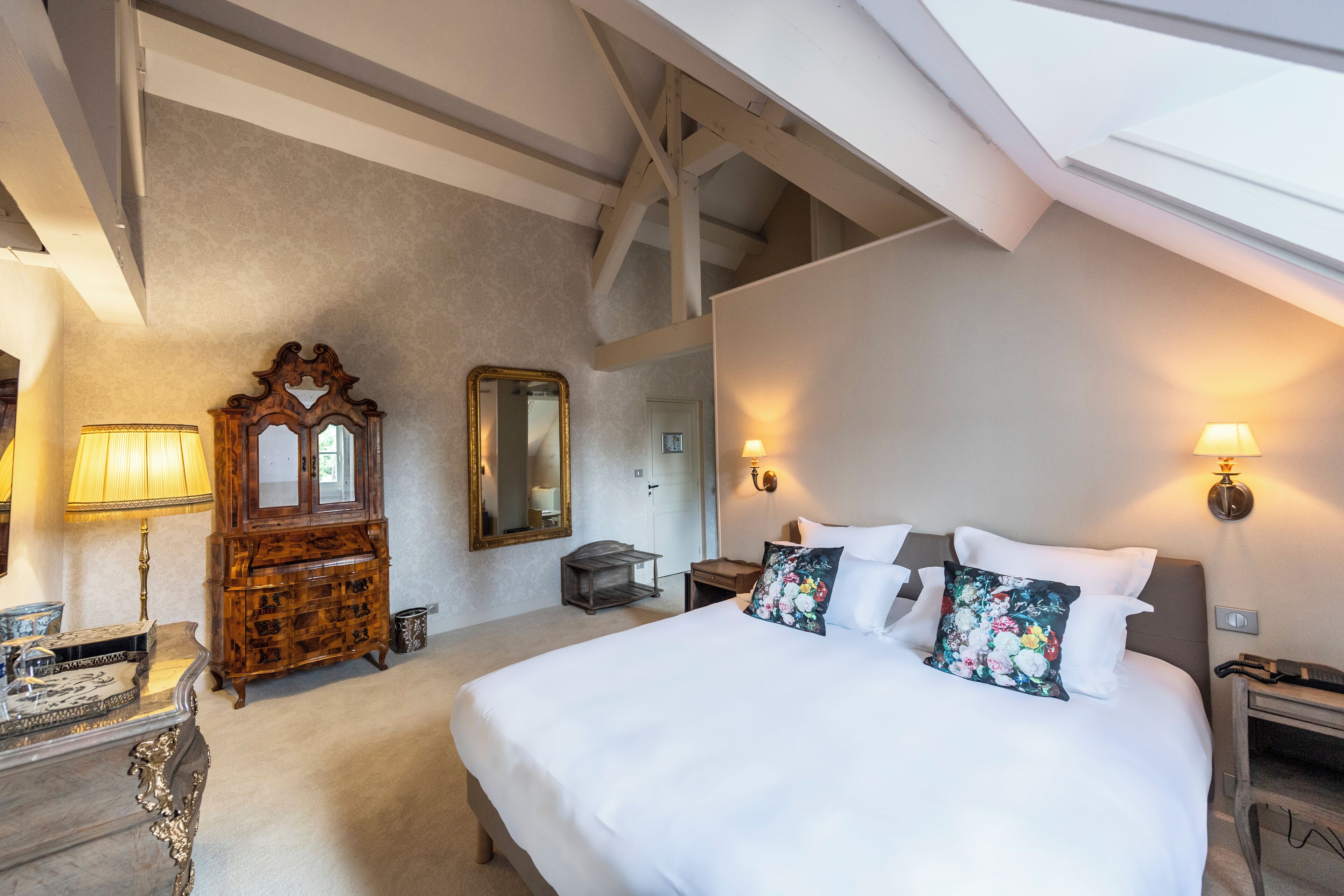 Una habitación de hotel con una cama grande, cómoda de madera y un espejo.