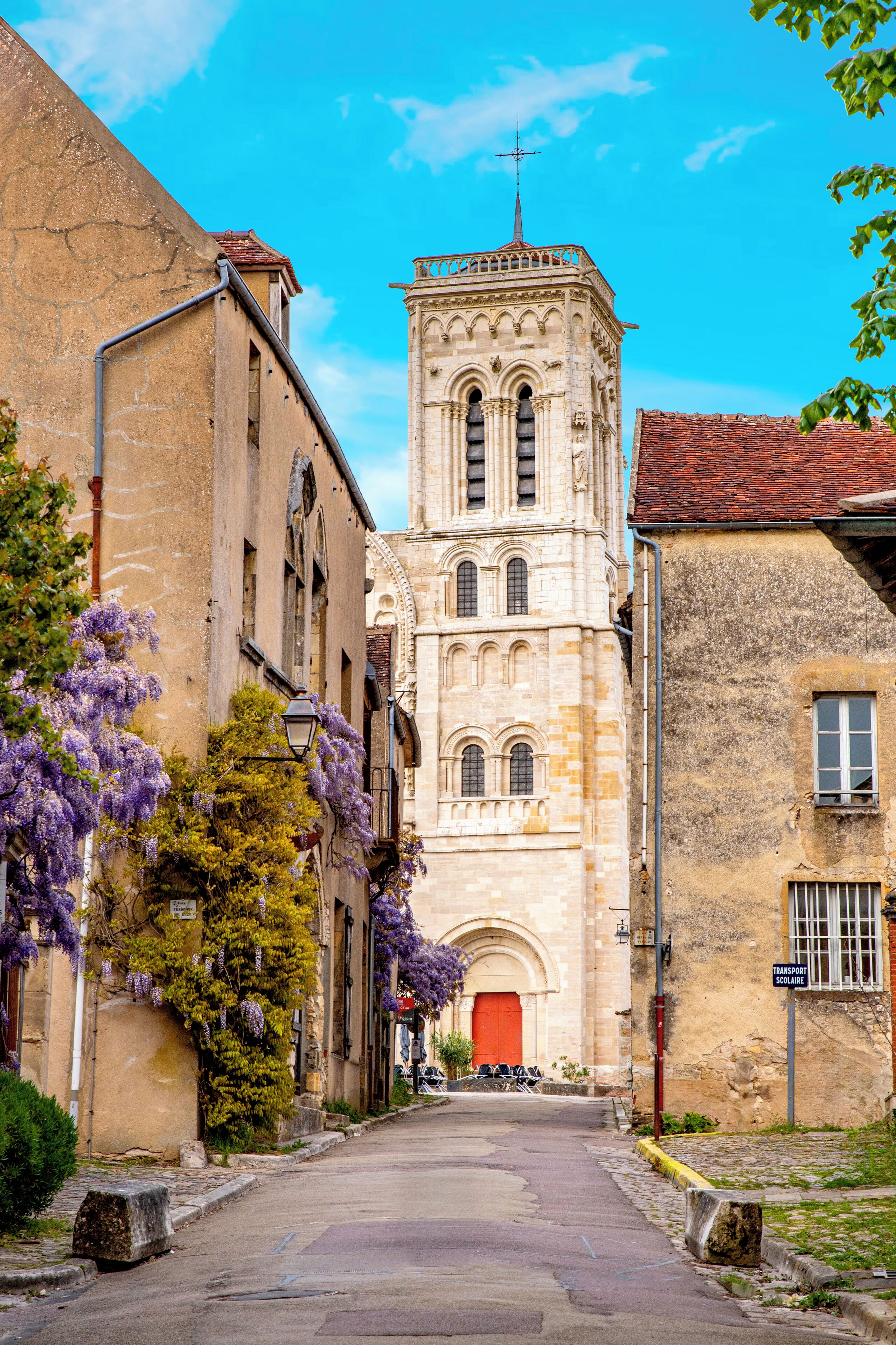A narrow street leading to a historic building with a bell tower.