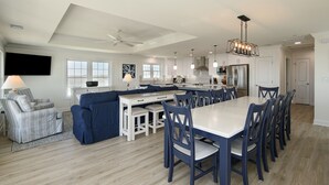 A modern kitchen with white cabinets, a large island, and a dining area with blue chairs.