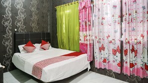 Et hotelværelse med en seng, grønne gardiner og lyserøde gardiner med Hello Kitty-mønster.