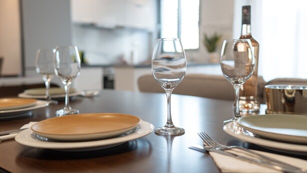 A dining table set with plates, glasses, and cutlery in a modern kitchen setting. - Pagrati Urban Living  (Athens)