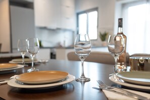 A dining table set with plates, glasses, and cutlery in a modern kitchen setting.