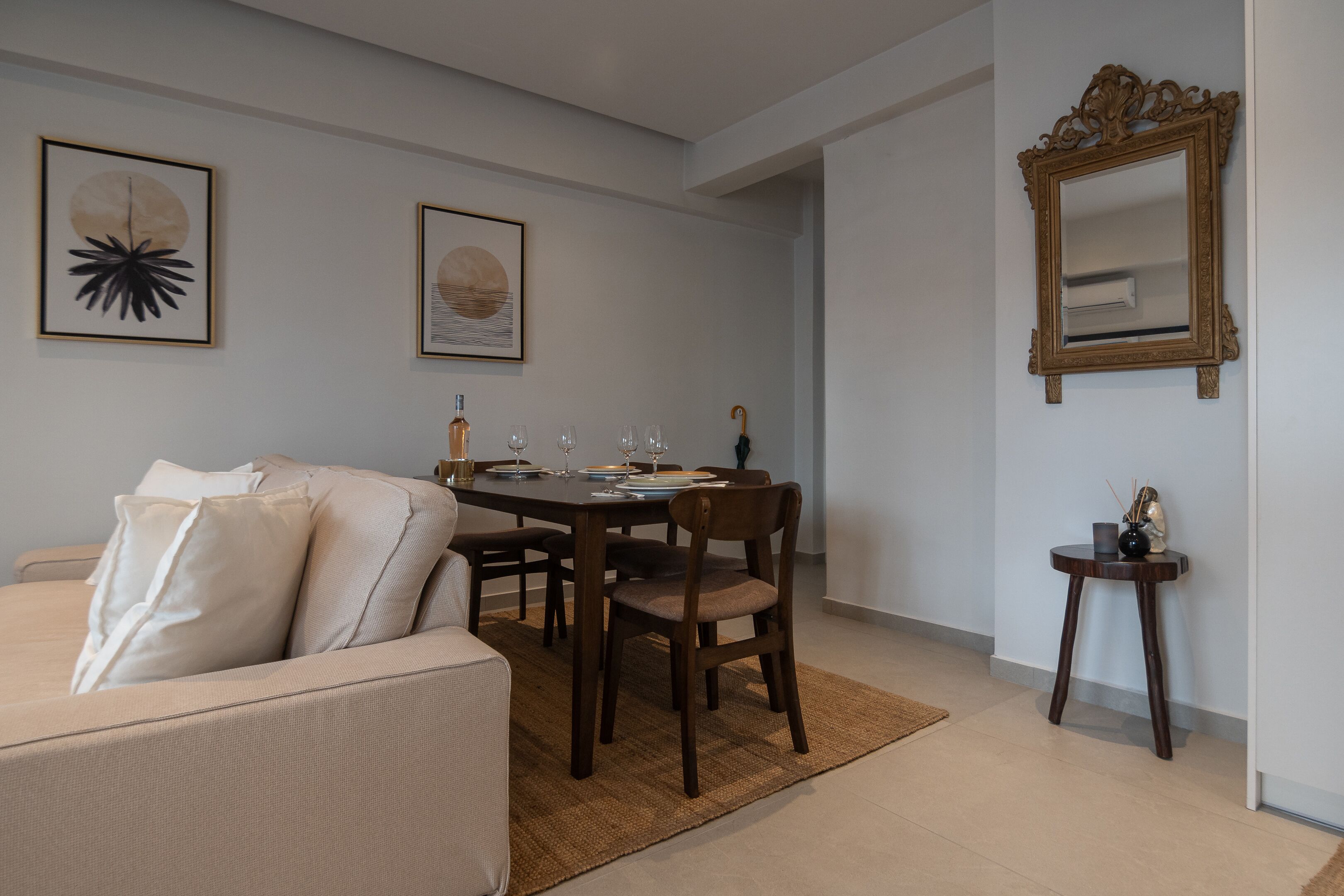 A dining area with a table set for four, a sofa, and a mirror on the wall.