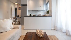 A modern kitchen with white cabinets, a central island, and a dining area with a table and chairs. - Pagrati Urban Living  (Athens)