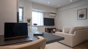 A modern living room with a sofa, a coffee table, and a laptop on a desk. - Pagrati Urban Living  (Athens)