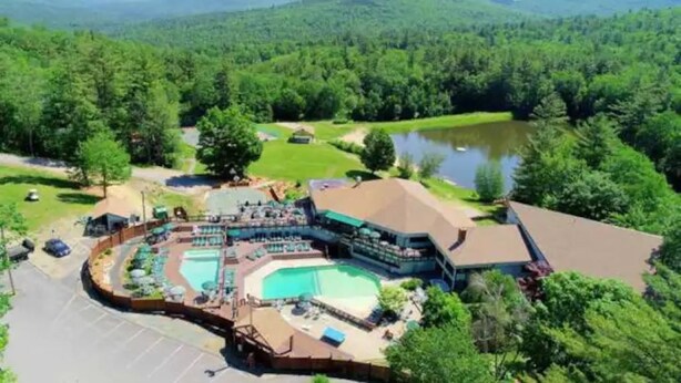 Ein Resort mit großzügiger Poolanlage, einer Gästelounge und Blick auf den umliegenden Wald und die Berge.