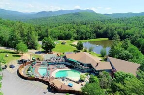 A resort with a large pool area, a guest lounge, and a view of the surrounding forest and mountains. - Spacious 4-bedroom townhome with amenities in Waterville Estates. (Campton)